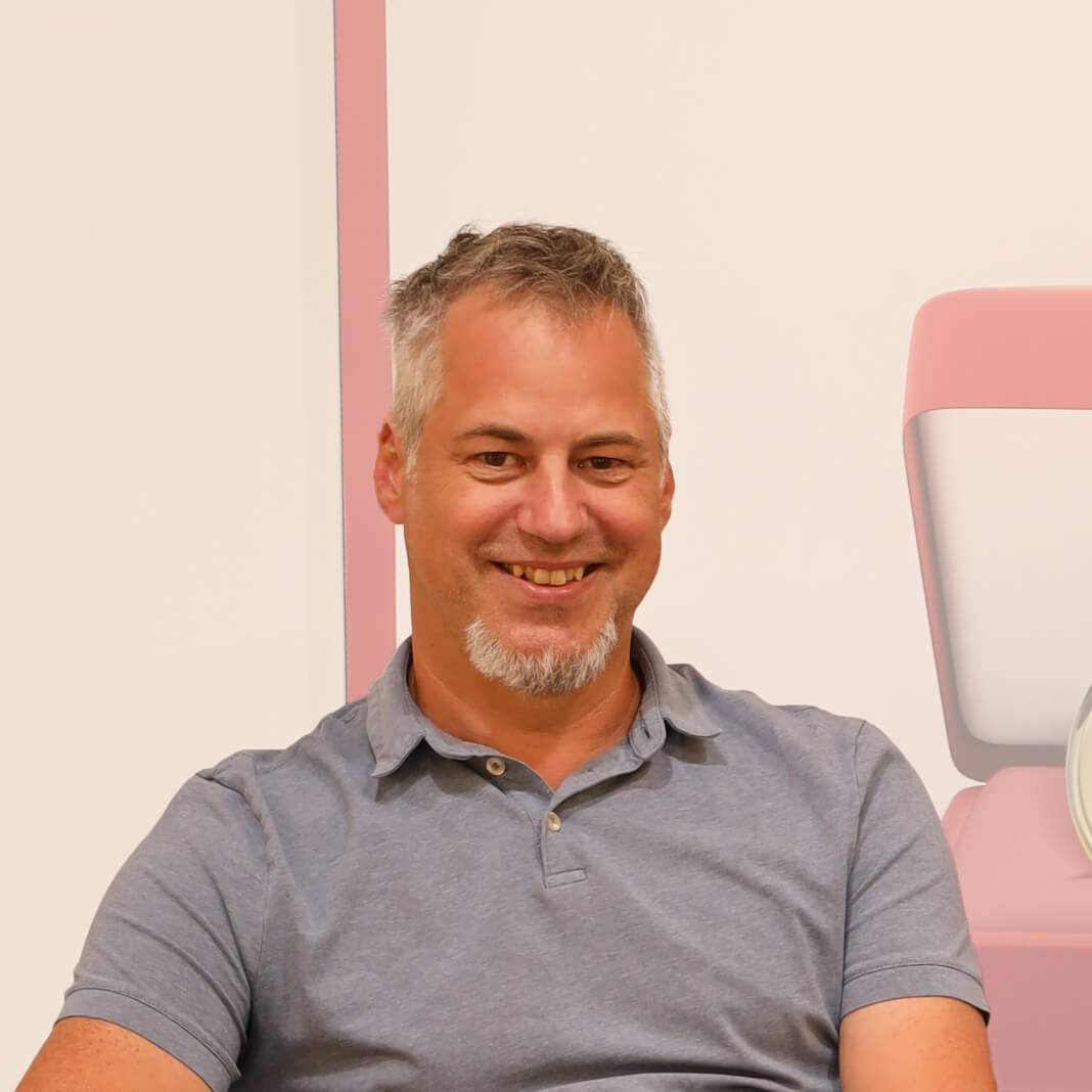 filialleiter-laechelnd-in-einem-polo-shirt-vor-einem-plakat-in-der-filiale