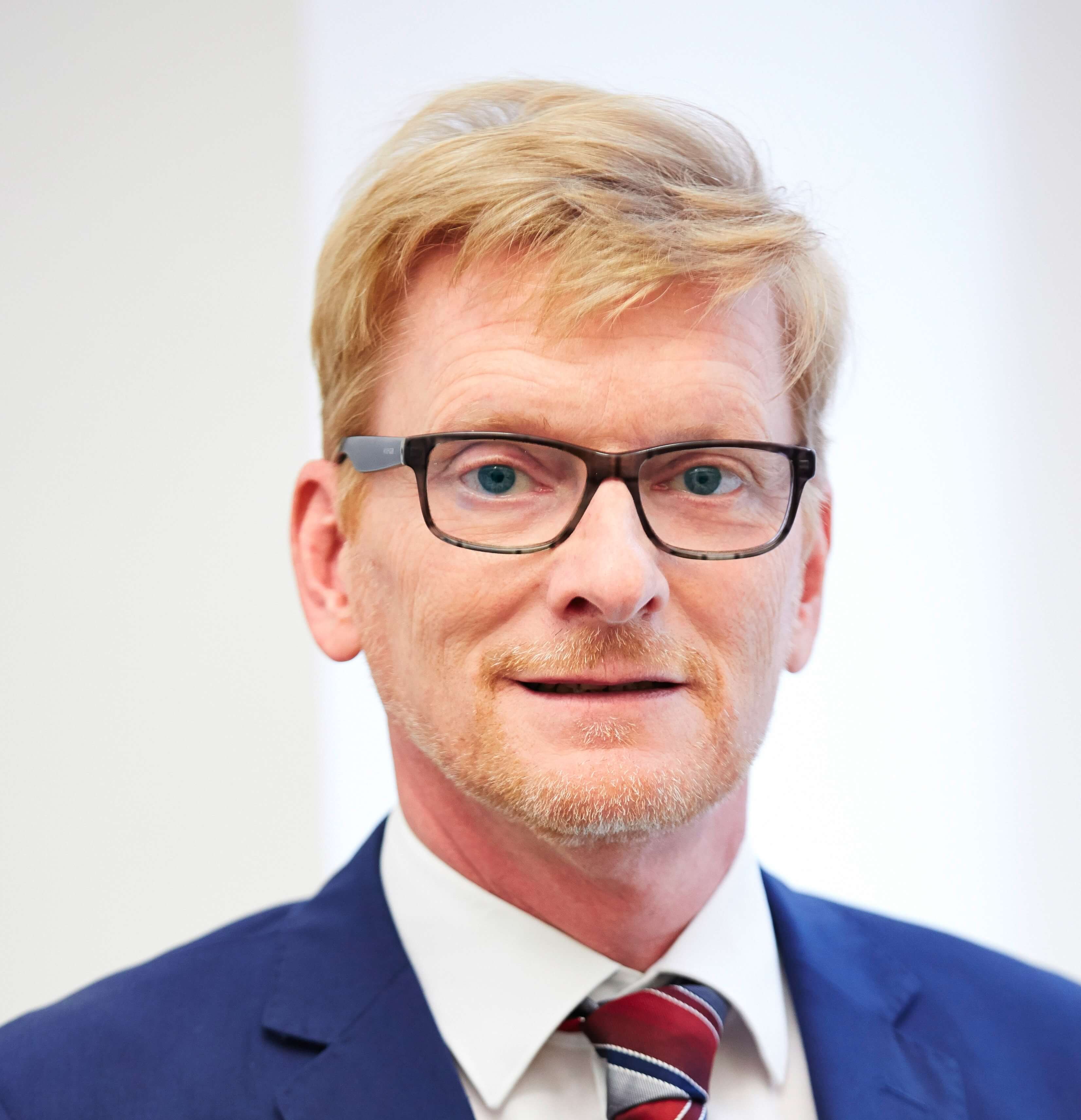 filialleiter-michael-holubowsky-in-blauem-anzug-mit-blonden-haaren-und-einer-brille