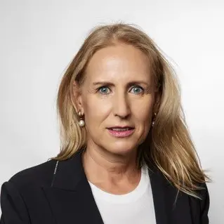 filialleiterin-in-weißem-shirt-und-blazer-vor-einer-weißen-wand