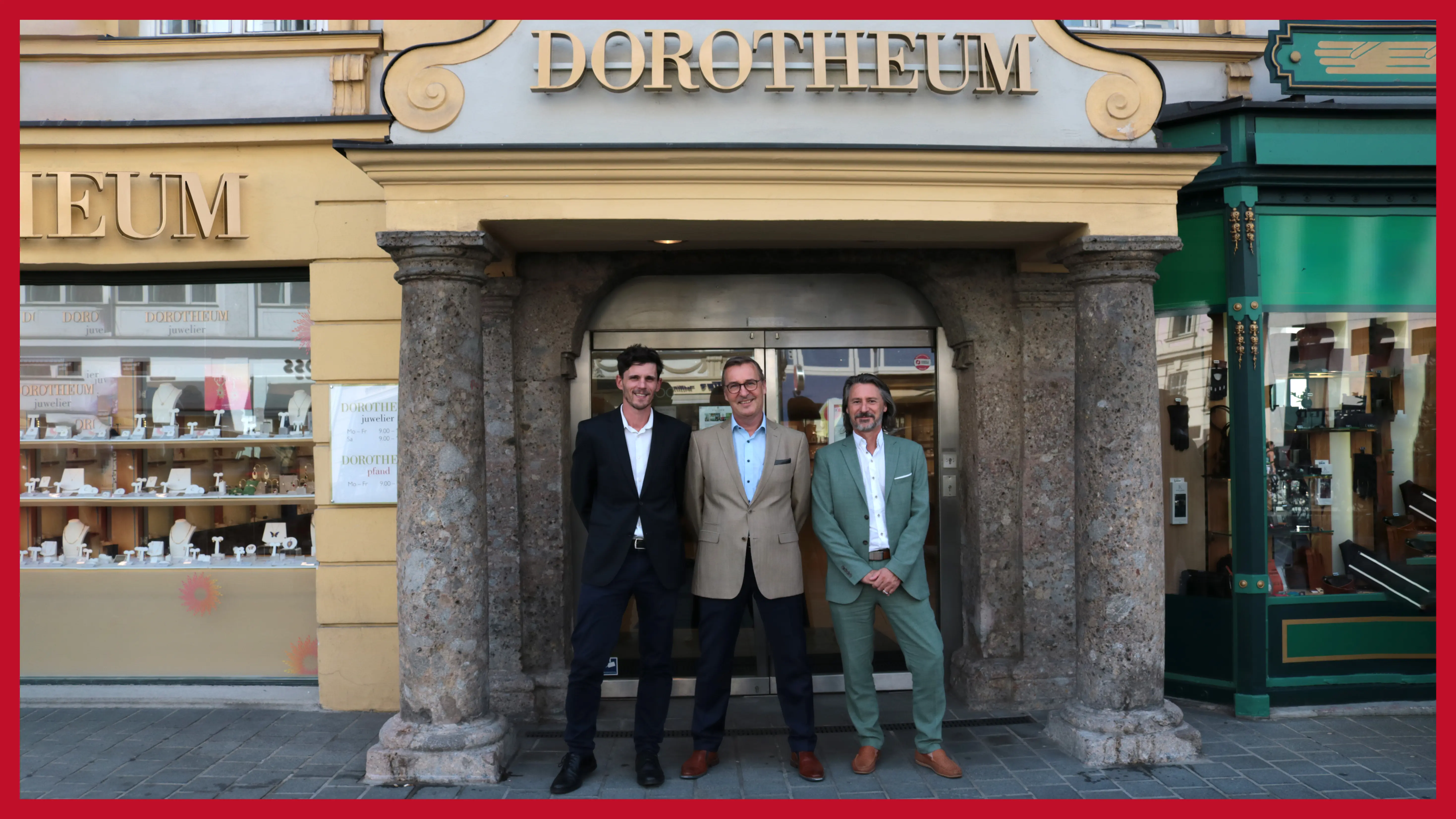 dreikoepfiges-team-vor-der-filiale-unter-einem-torbogen-aus-marmor