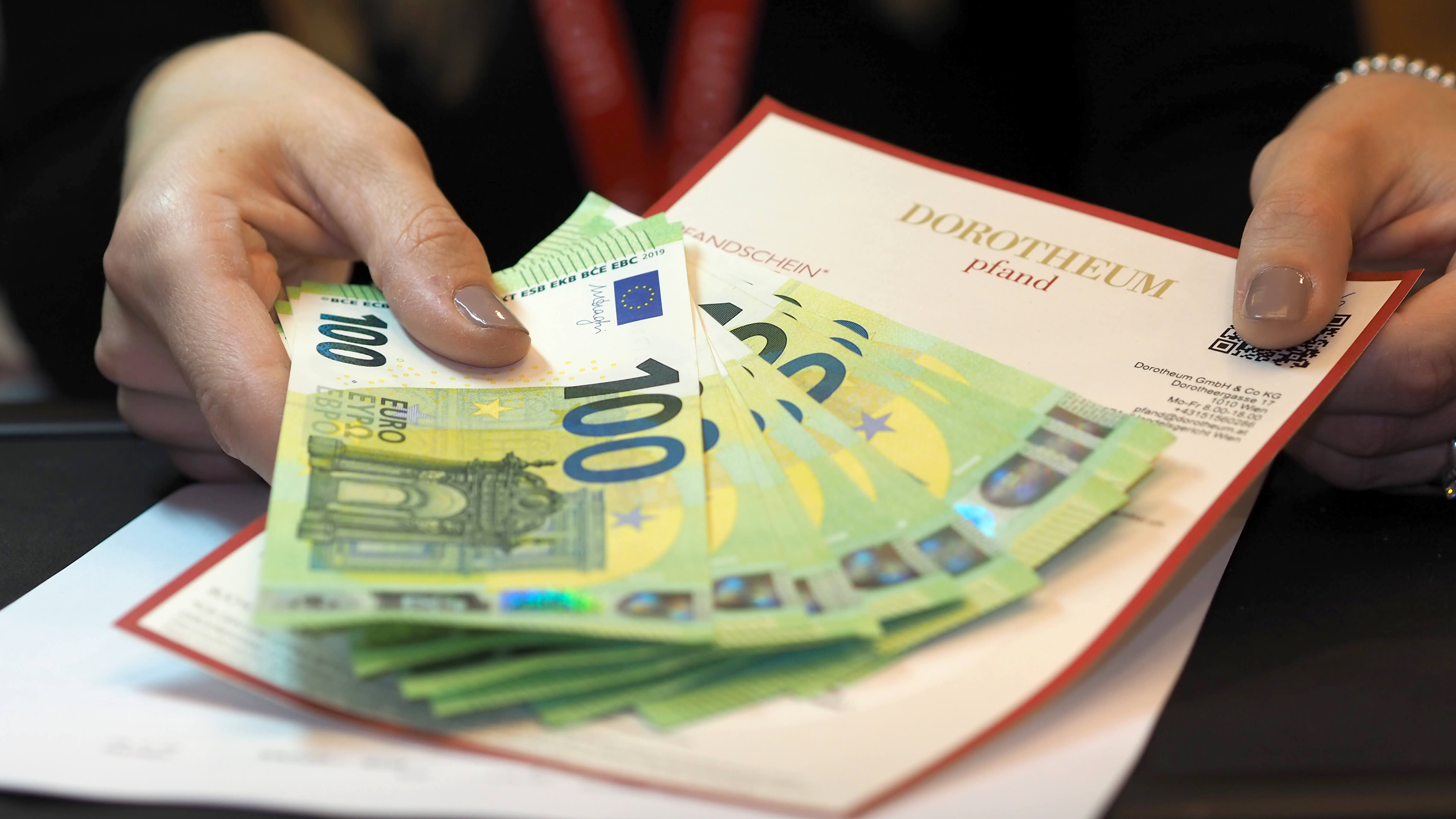 Geldscheine und Pfandschein in einer Damenhand