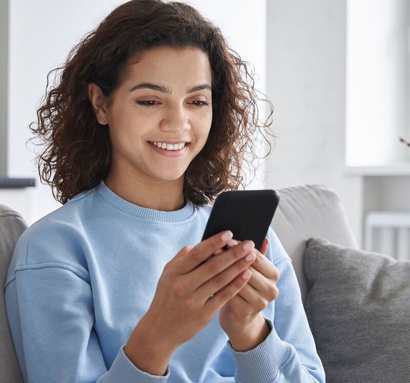 Junge Frau am Sofa mit Smartphone