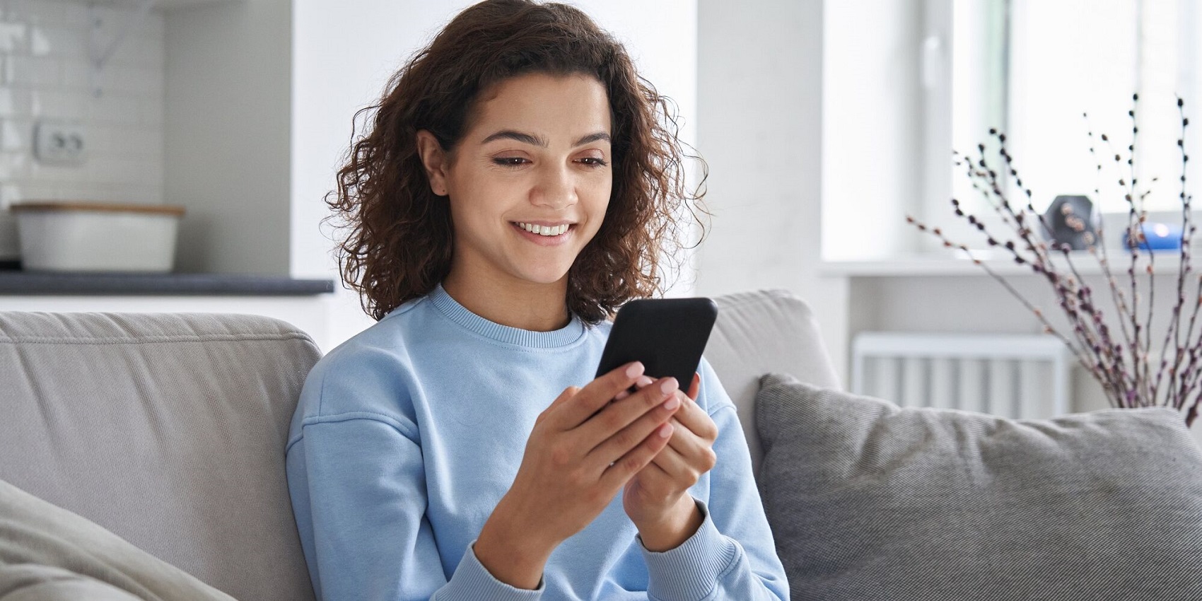 Junge Frau am Sofa mit Smartphone