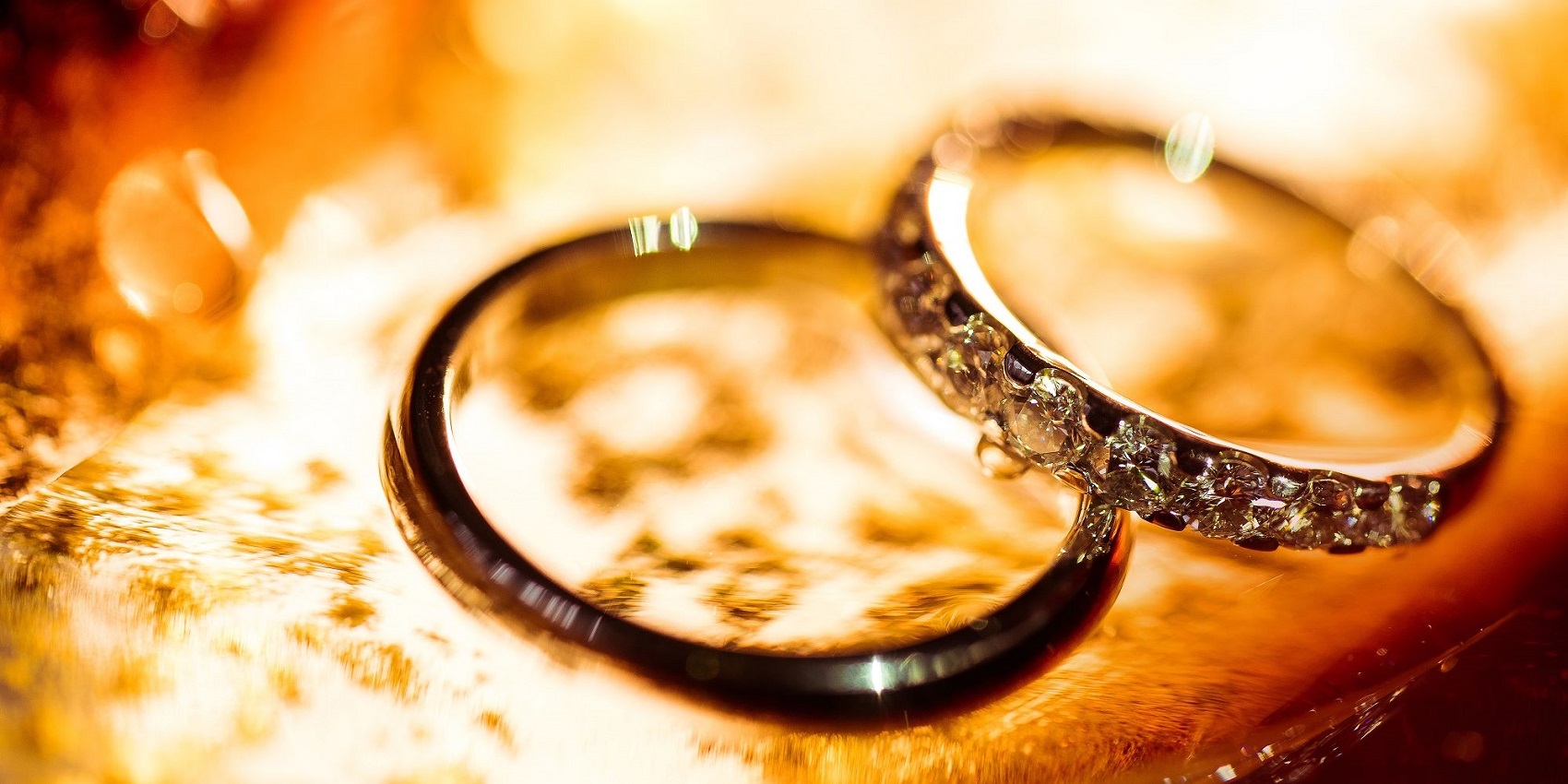 ein Paar Eheringe auf orangem Hintergrund.